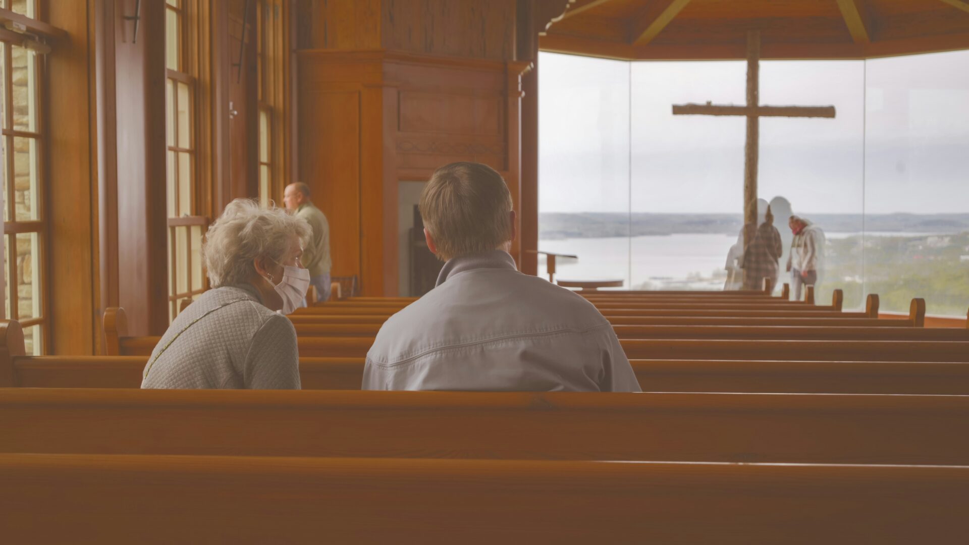 Two people sitting on pews inside a church