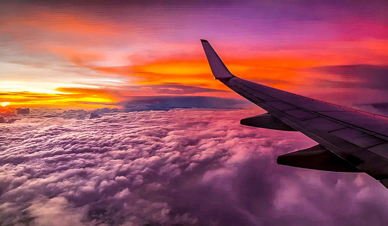 An airplane wing is set against a sunset sky.