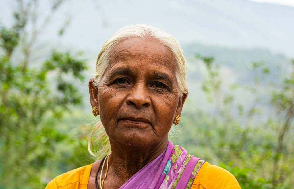 A Hindu woman in a yellow an purple shirt looking at the camera