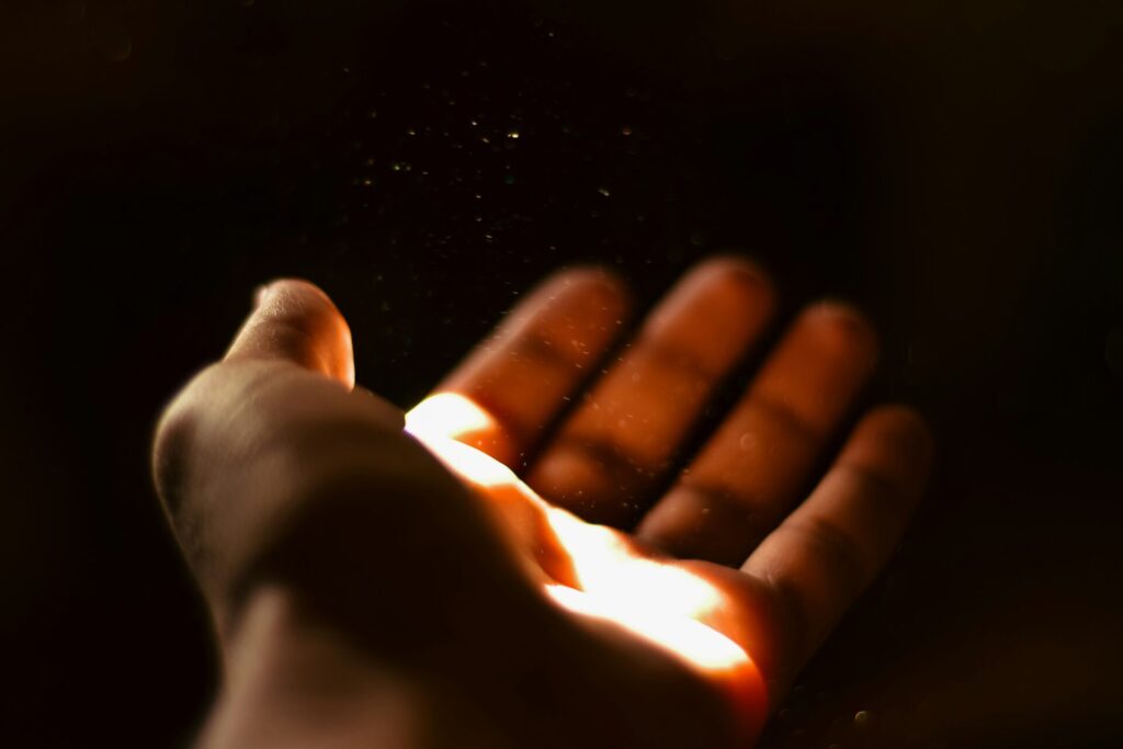 A person extending their hand with a ray of light illuminating it