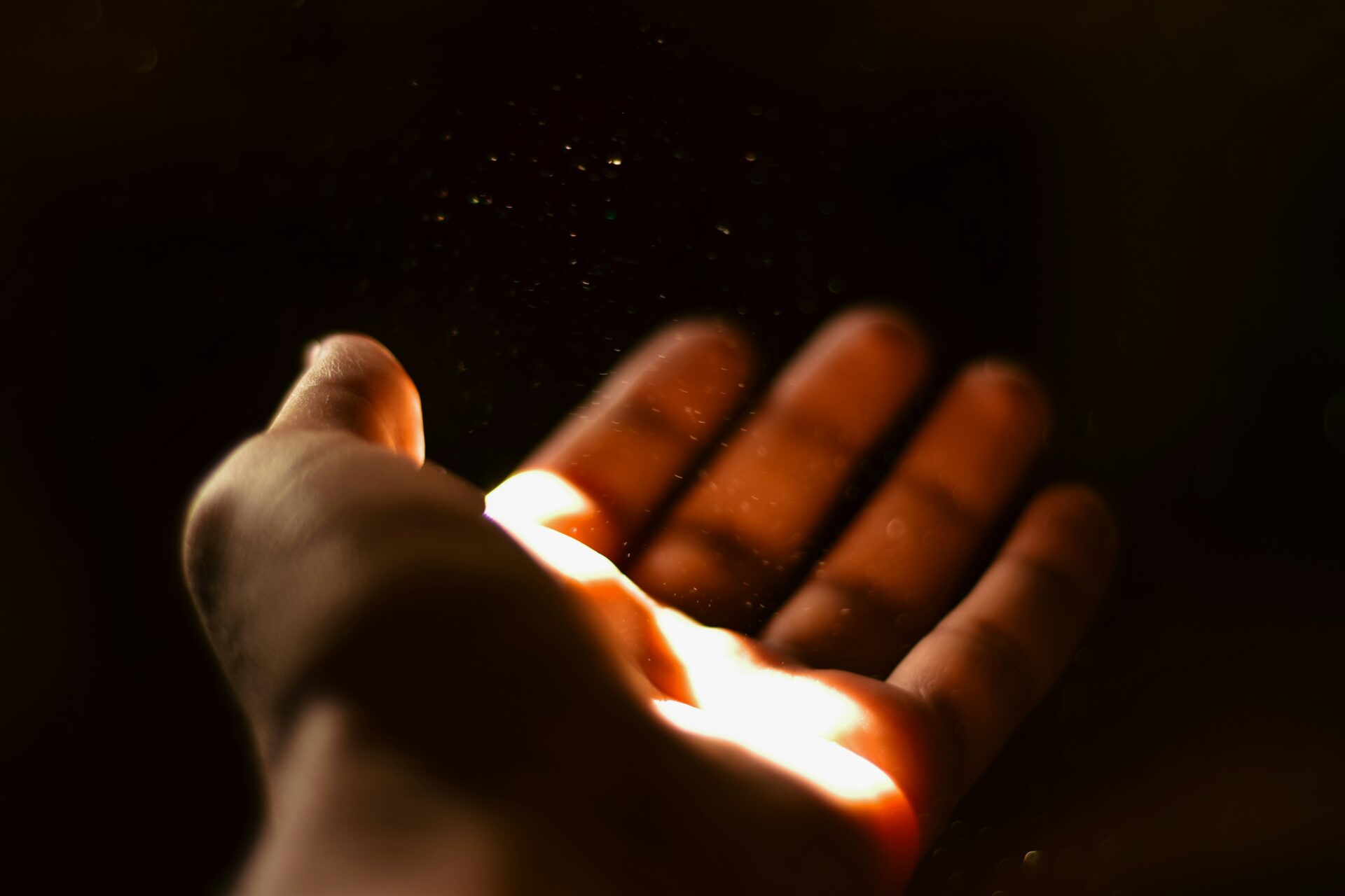 A person extending their hand with a ray of light illuminating it