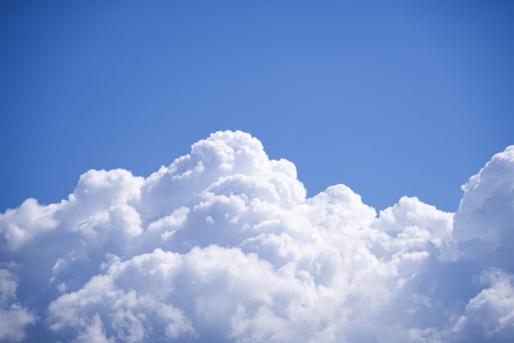 Blue sky with large, white, fluffy cumulus clouds filling the lower half of the image.