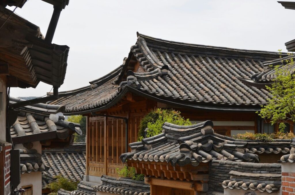 Traditional Korean hanok houses with curved tiled roofs and wooden structures clustered closely together.