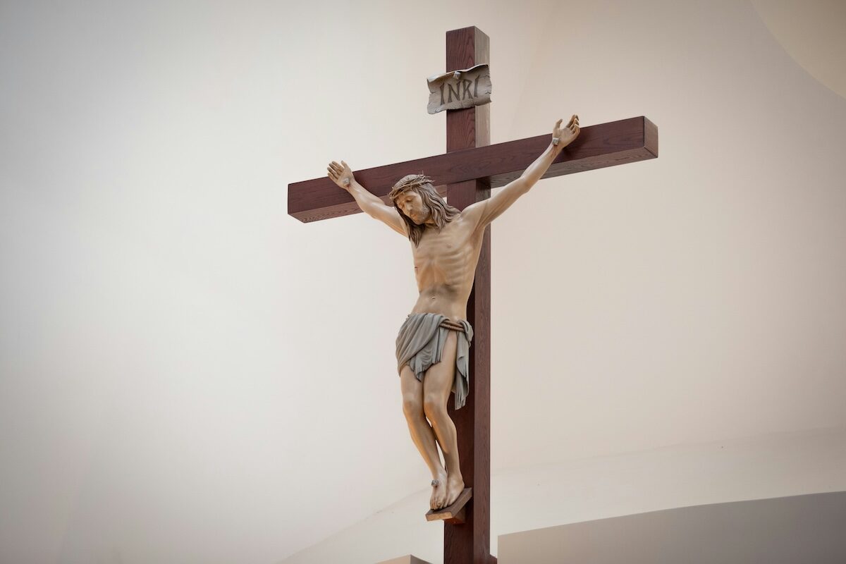 A wooden crucifix depicting Jesus Christ nailed to the cross, with a white background.