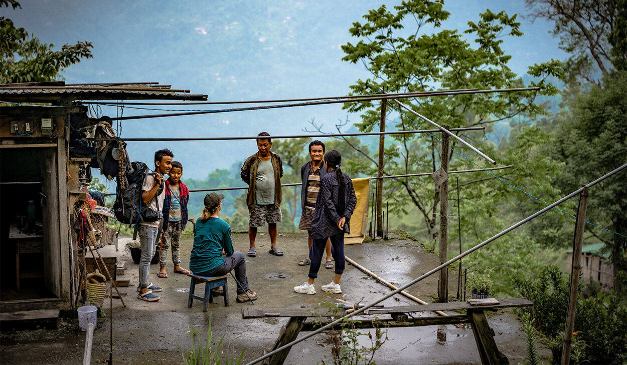 People in a circle listen as a woman shares the gospel.