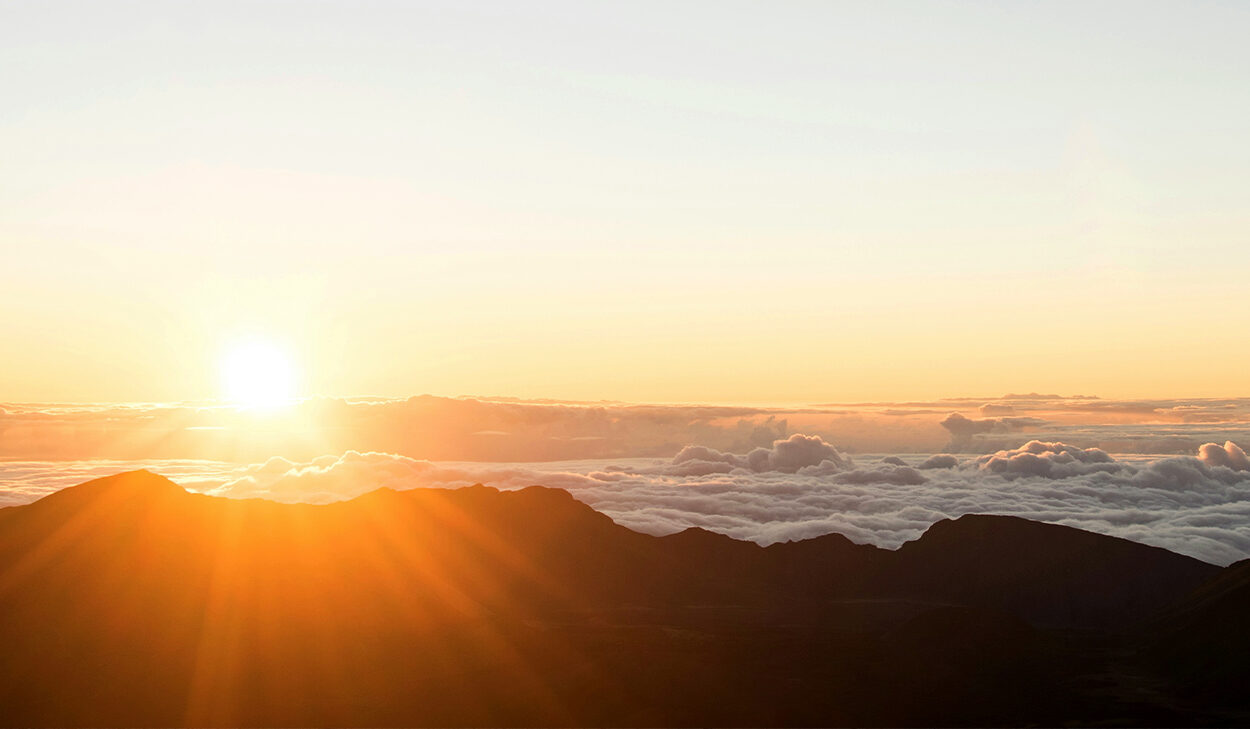 The sun rises over a mountain and the clouds.