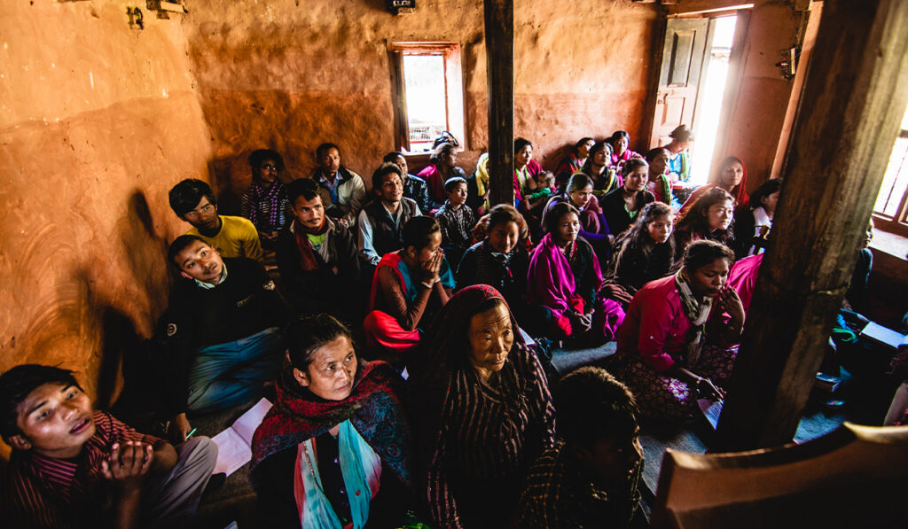 People in a house church in South Asia sit on the ground.