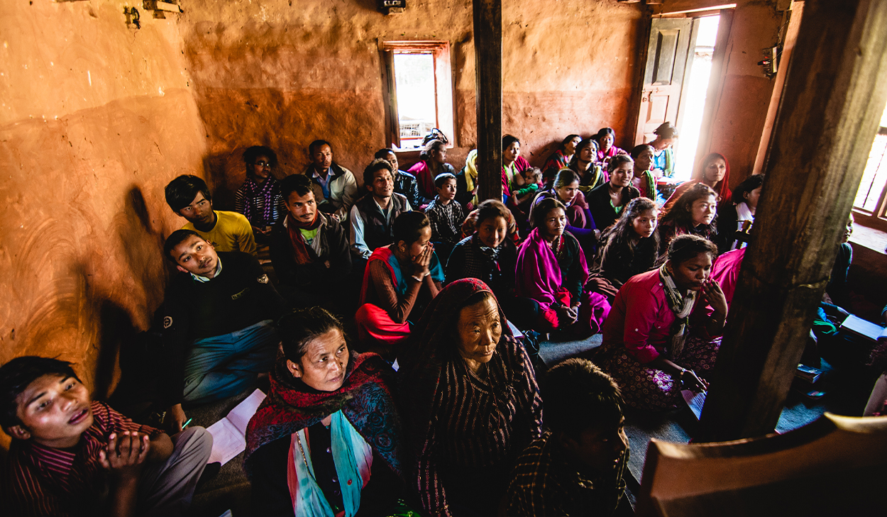 People in a house church in South Asia sit on the ground.