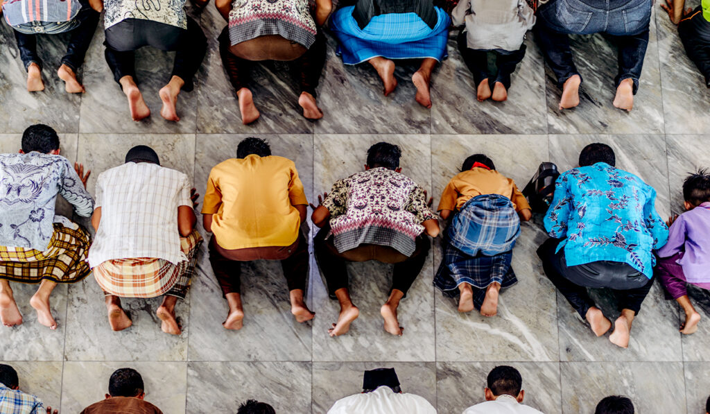 Muslim men pray face down inside a mosque.