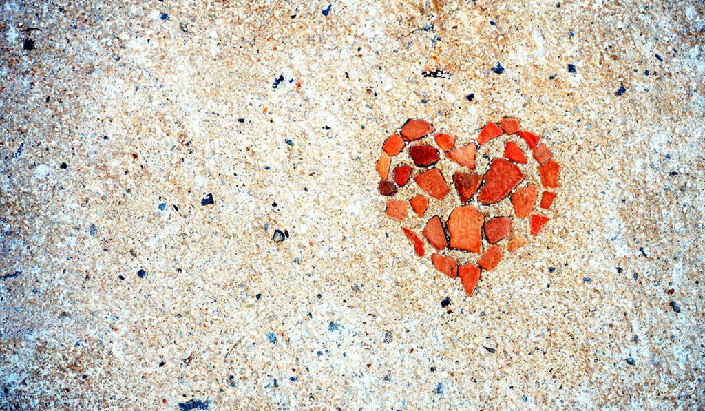 Red stones set in concrete form the shape of a heart.