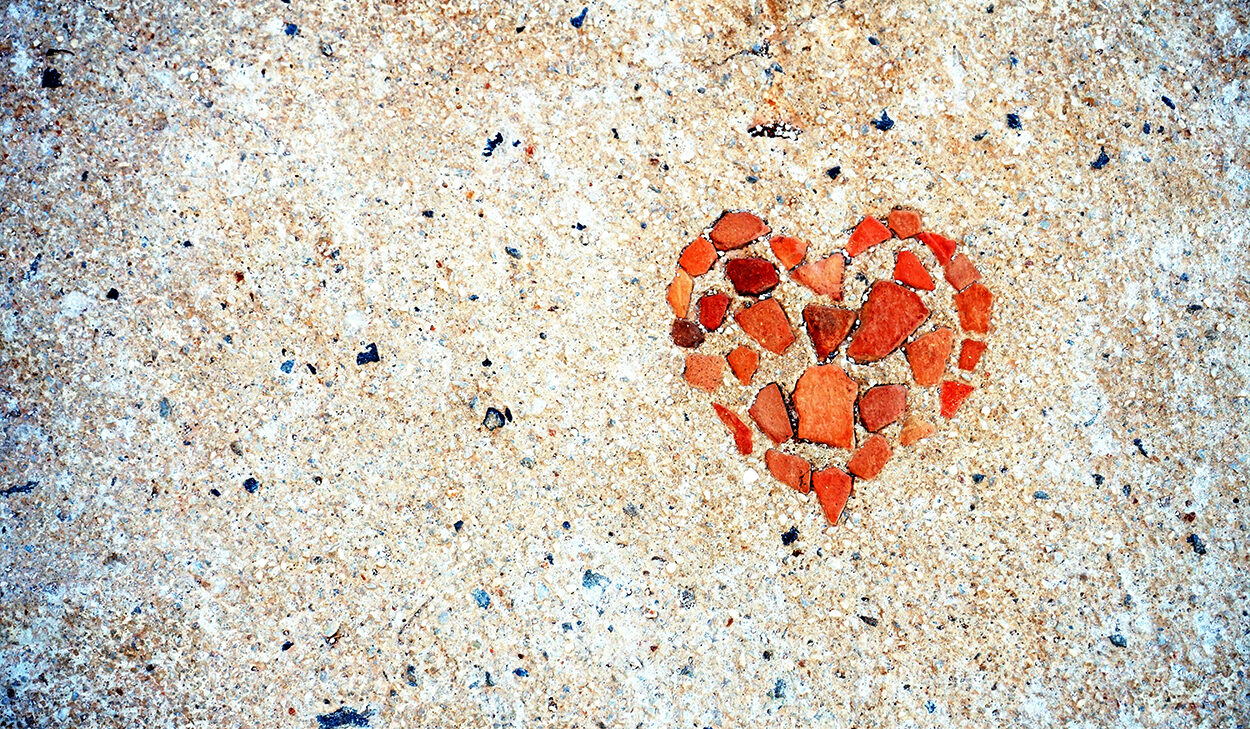 Red stones set in concrete form the shape of a heart.