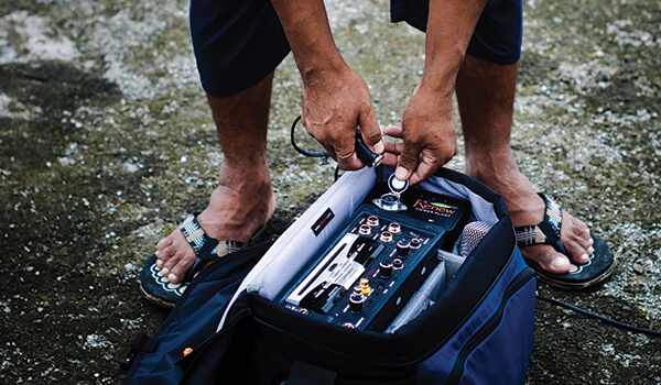 Close up of a person plugging a cable into a port on video equipment in a camera bag.