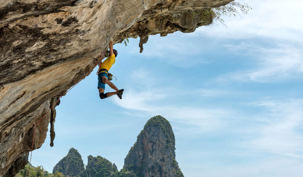 A man rock climbs on a cliff.