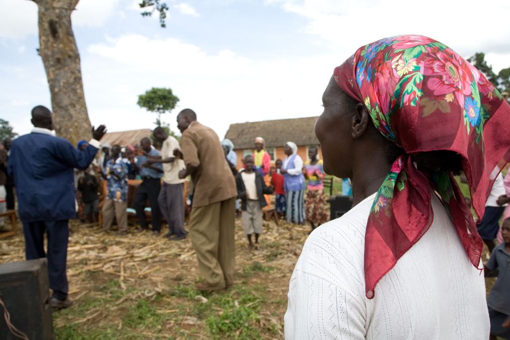 woman looks on to a church service in africa taking place outside