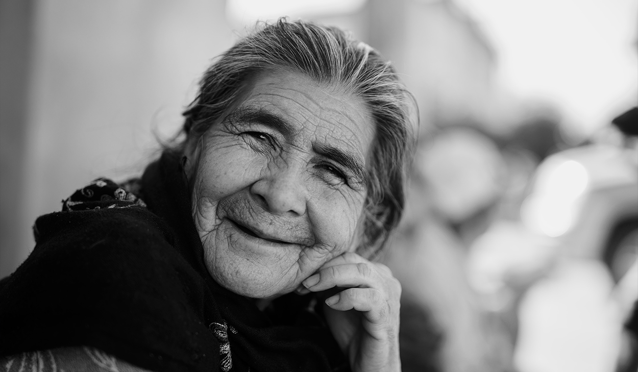A black and white photo of an elderly woman who is smiling.