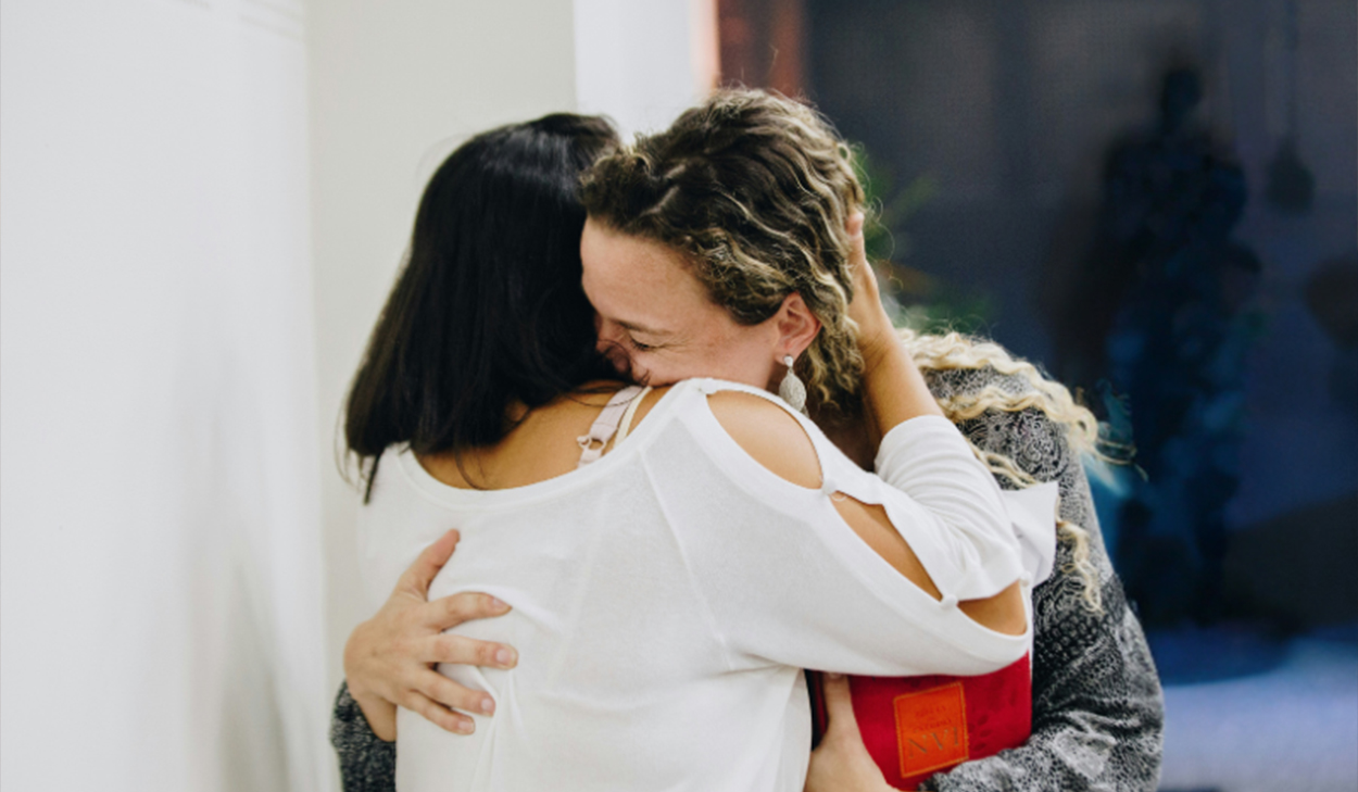 Two women embrace.