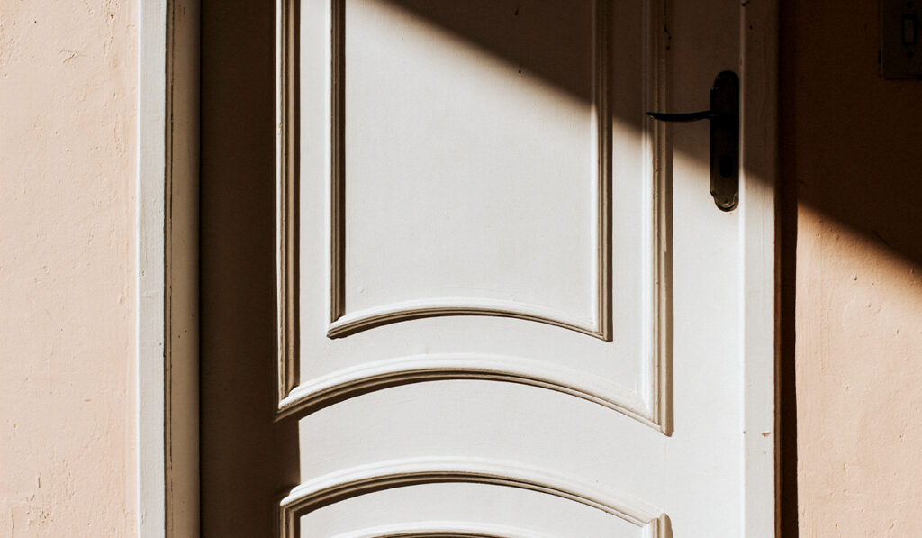 A shadow is cast at the top of a white door.