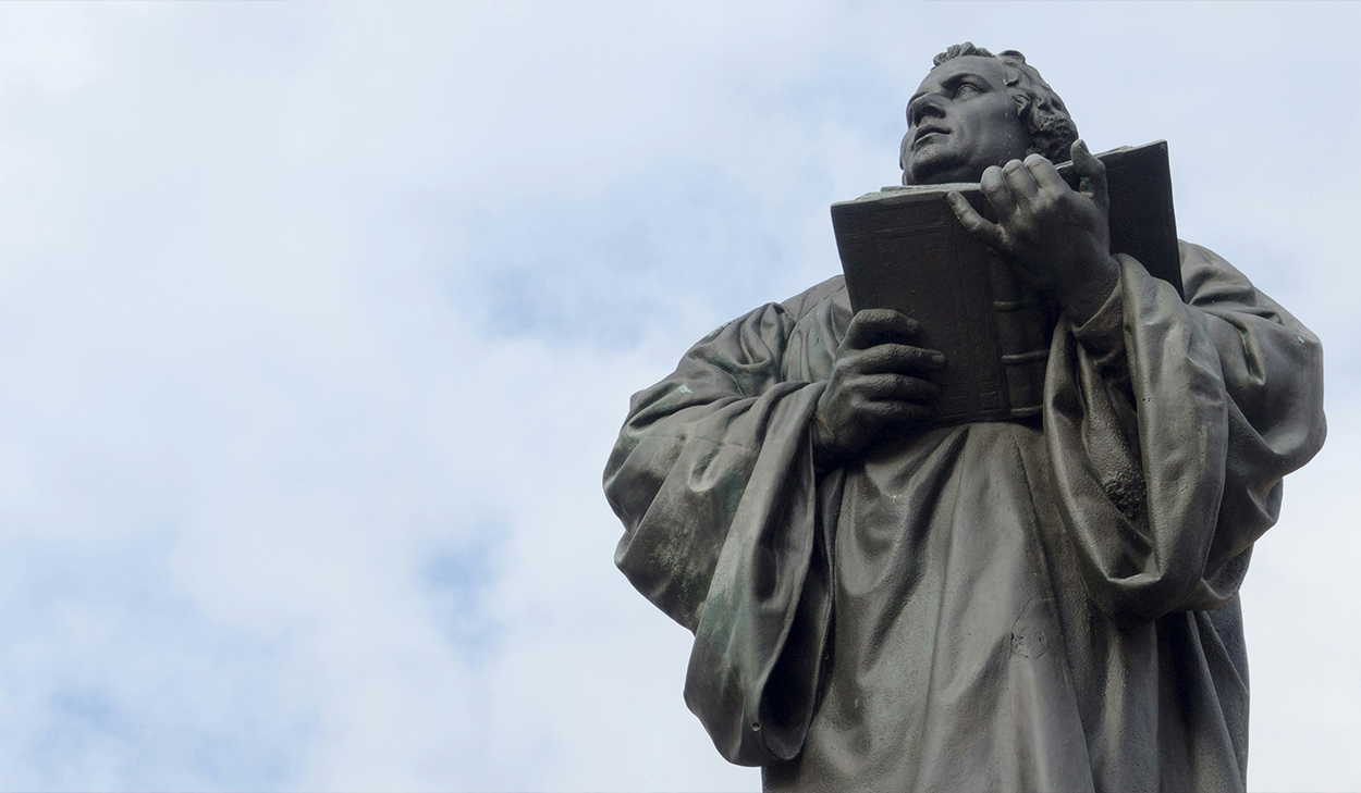 A statue of a man looking up and holding a book.