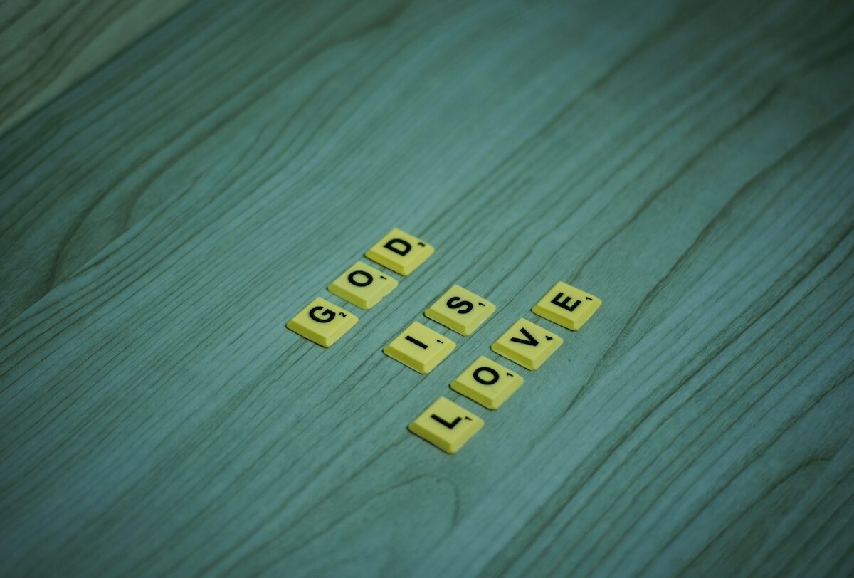 Yellow letter tiles on a wooden surface spell out the phrase GOD IS LOVE.