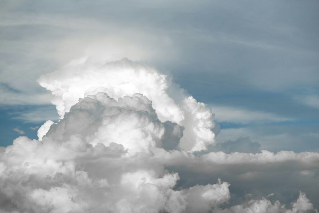Towering cumulus clouds against a blue sky with scattered lighter clouds.