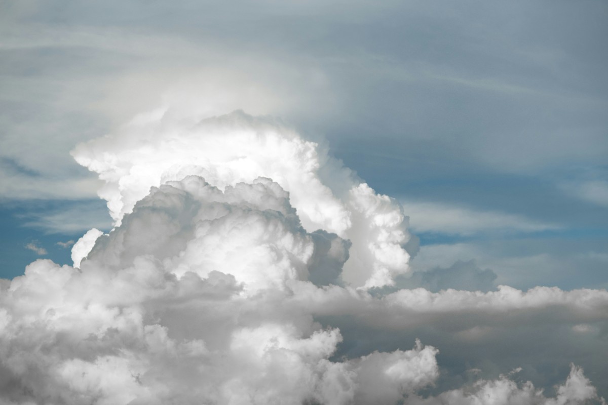 Towering cumulus clouds against a blue sky with scattered lighter clouds.