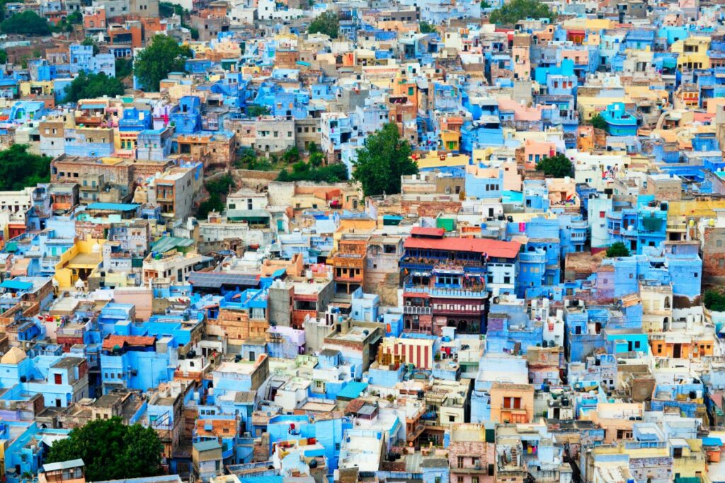 Aerial view of a densely packed cityscape with numerous blue-painted buildings and some others in earthy tones.