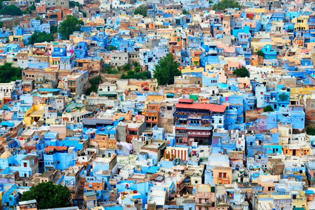 Aerial view of a densely packed cityscape with numerous blue-painted buildings and some others in earthy tones.