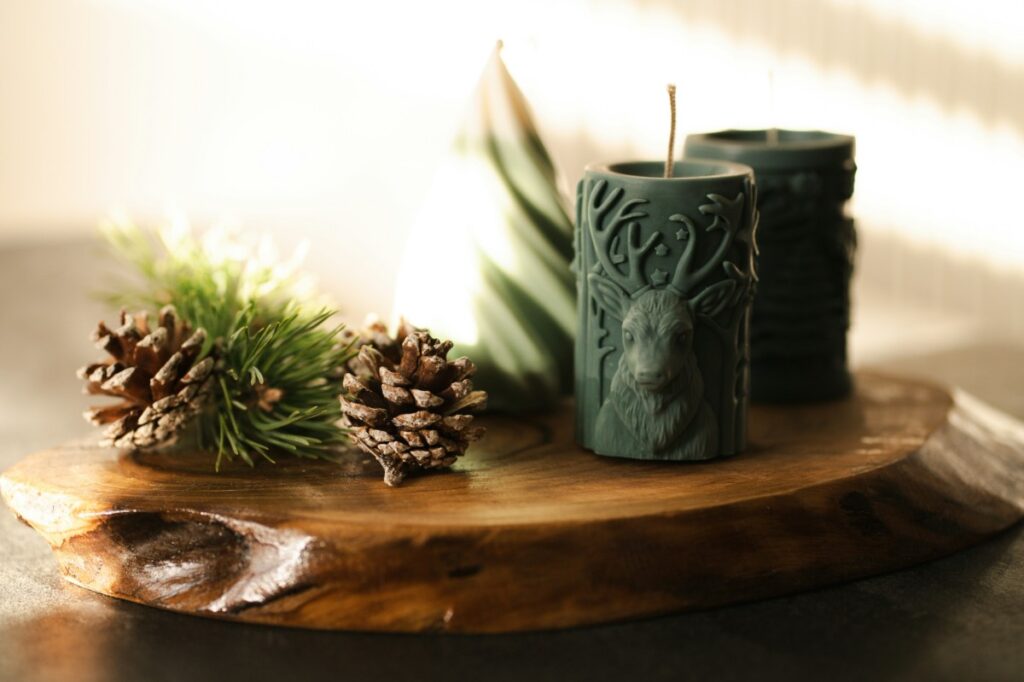 Three dark green candles and pinecones placed on a wooden tray, creating a rustic decorative arrangement.