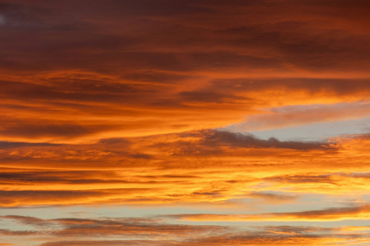 A vibrant orange and red sunset sky with scattered clouds.