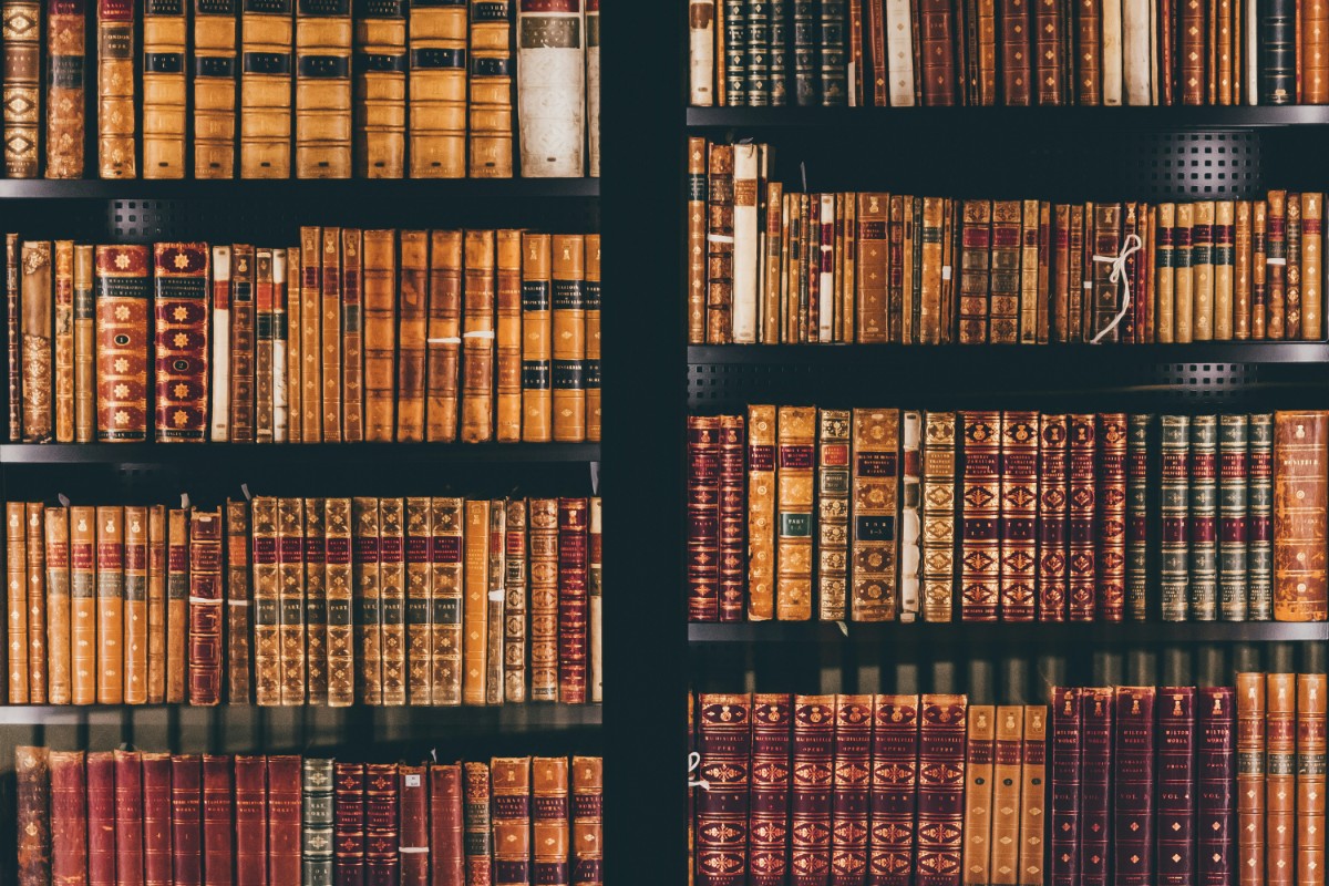 Books with ornate leather covers are neatly arranged on wooden shelves.