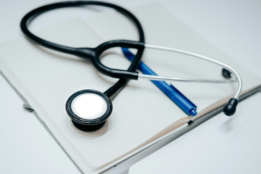A stethoscope and blue pen resting on an open notebook.
