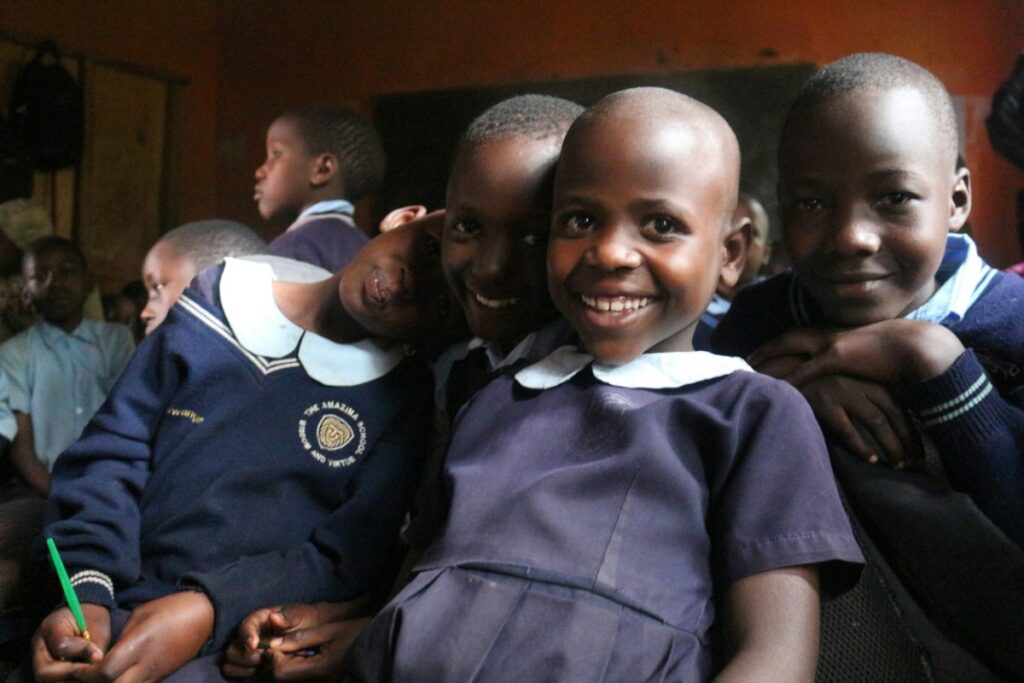 Children in school uniforms smiling and posing in a classroom.