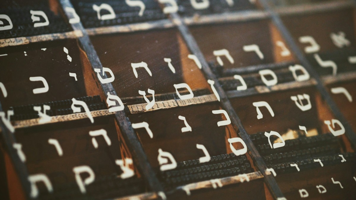 A close-up of Hebrew letters arranged in rows on a wooden surface.