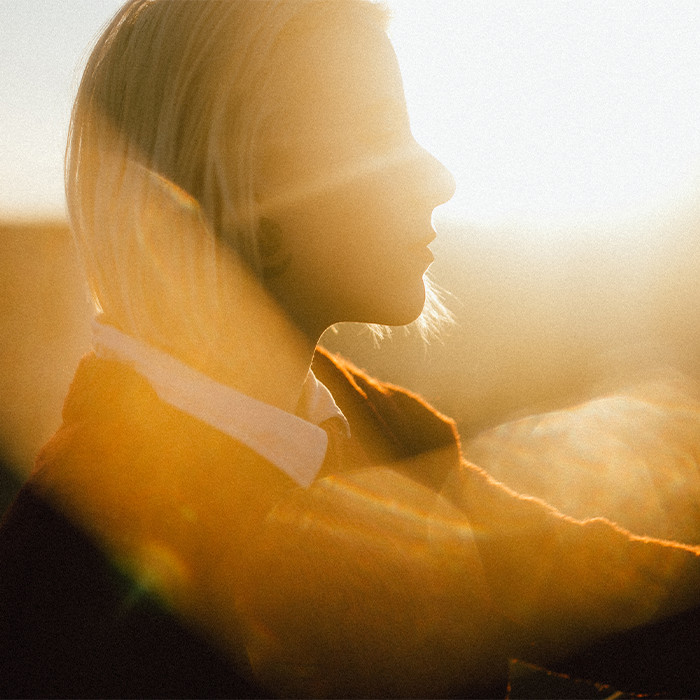 A women's face, very bright and glowing from the sun reflecting off of her.