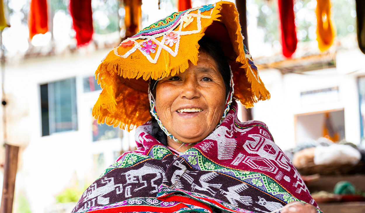 A woman in colorful, traditional clothing from Latin America smiles at the camera.