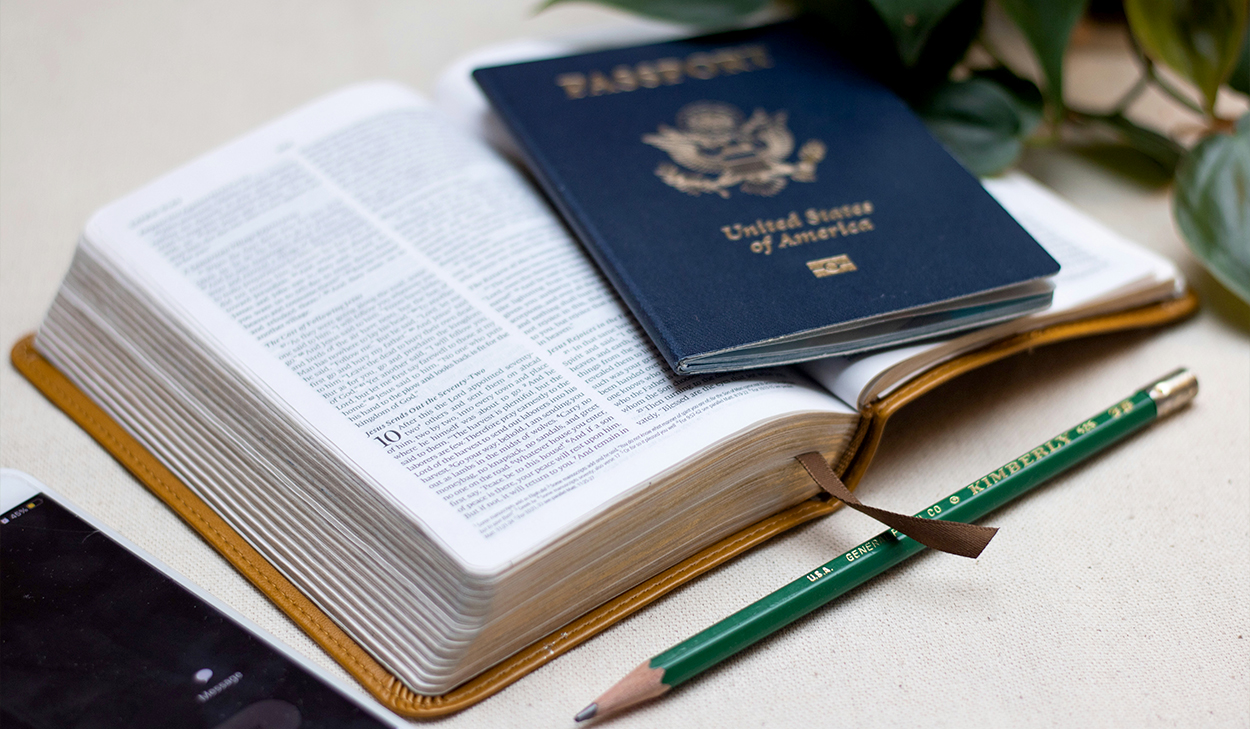 A passport sits on top of a Bible that is open to Luke 10.