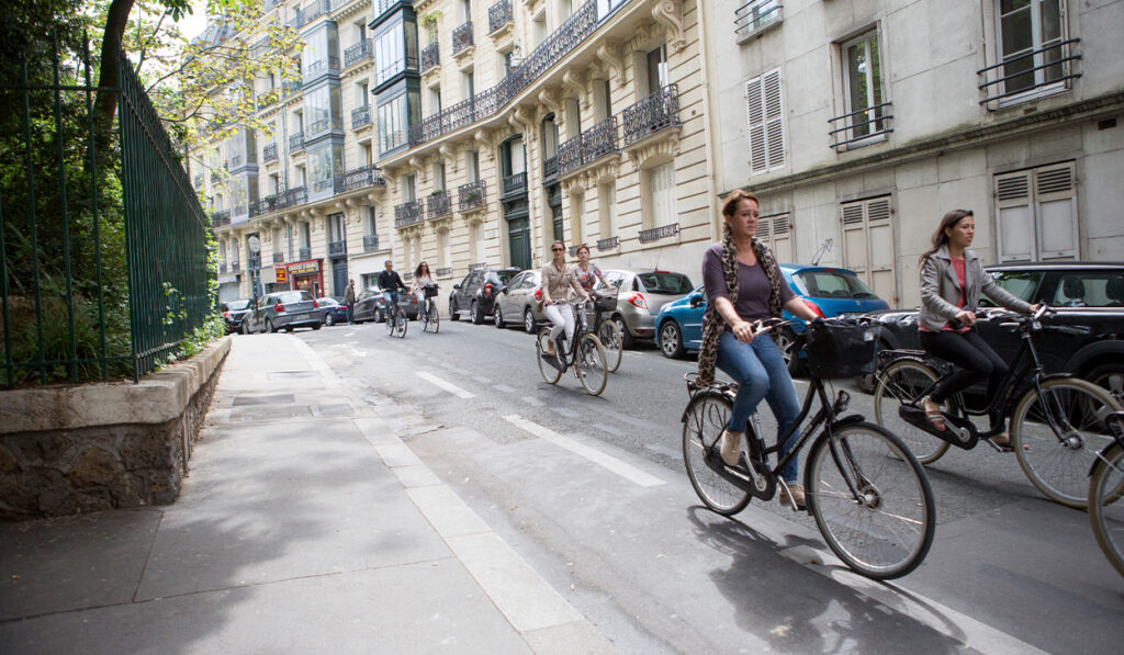 Women bike down a European street.