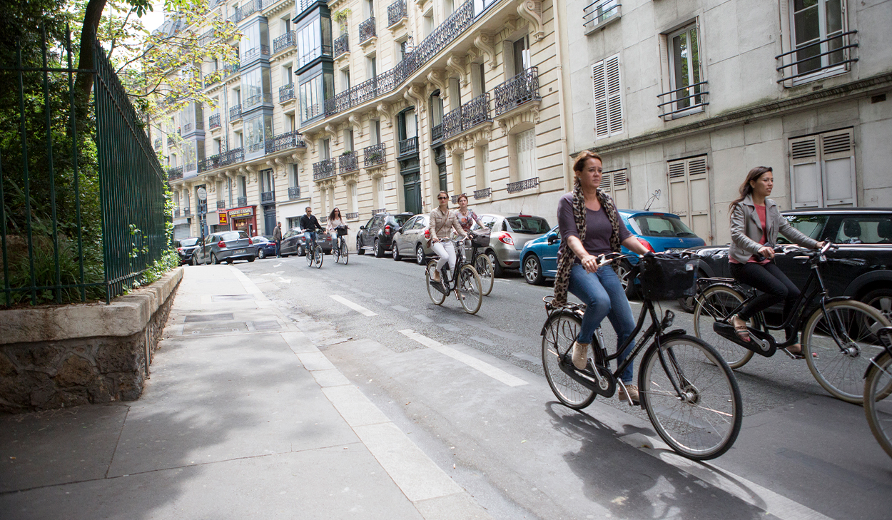 Women bike down a European street.
