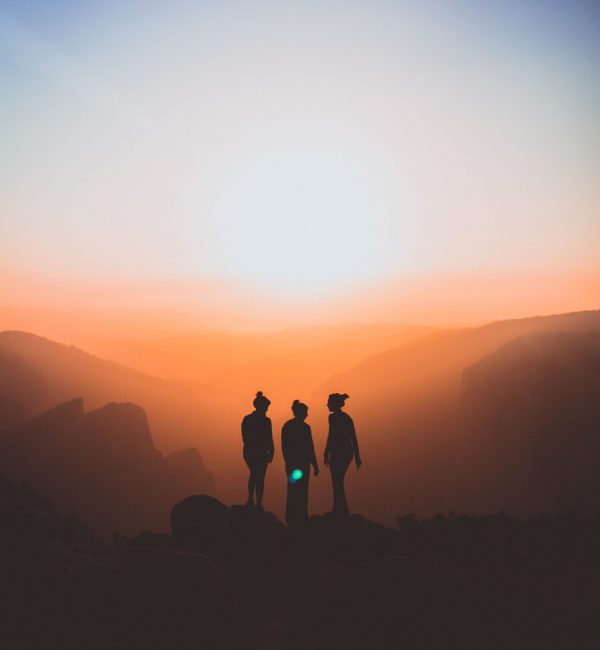 Three women standing on a mountain, silhouetted
